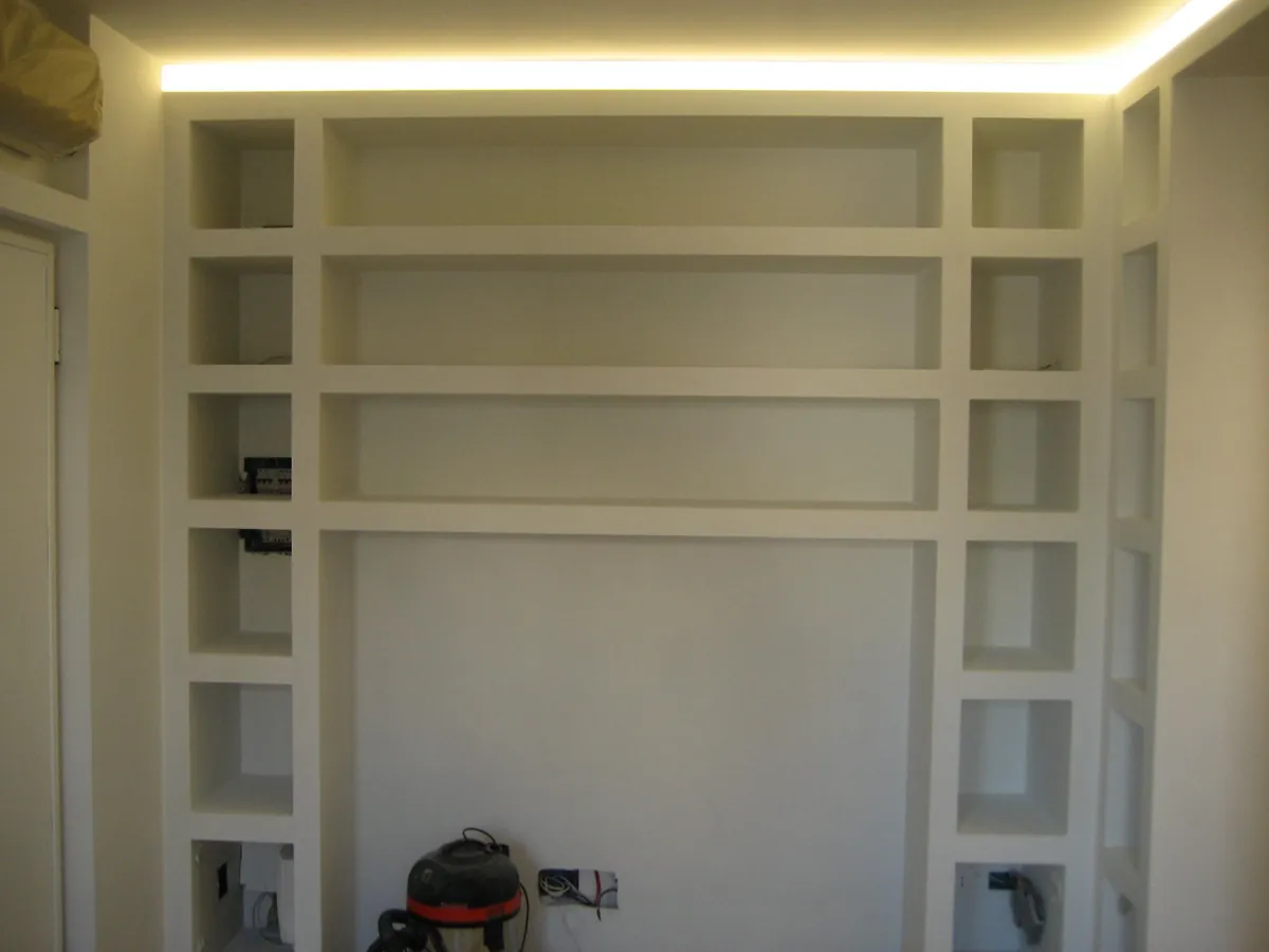 Libreria a parete in cartongesso con nicchie e striscia LED nel controsoffitto